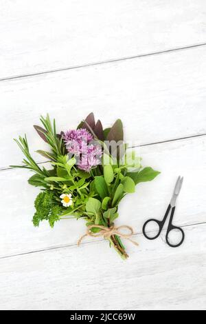 Herbes attachées dans un bouquet pour l'assaisonnement alimentaire et utilisé dans la médecine à base de plantes pour diverses maladies. Concept de soins de santé sur bois blanc rustique. Banque D'Images