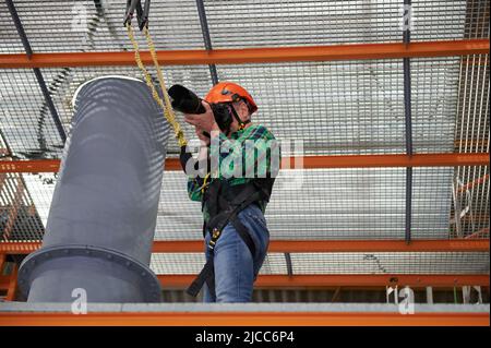 Photographe travaillant en hauteur attaché avec un harnais de sécurité et un casque Banque D'Images