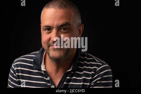Homme hispanique souriant avec un sourcil élevé sur un fond noir avec espace de copie Banque D'Images
