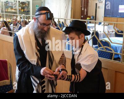 Quelques semaines avant sa cérémonie et sa célébration de Barmitzvah Menachem Mendel Pink est aidé à mettre le tephillim pour la première fois par son père Rabbi Yehuda Pink de la Solihull et de la Congrégation hébraïque de district dans les Midlands de l'Ouest et regardé par son grand-père M. Phaivish Pink, Directeur de l'école de grammaire juive de Manchester, lors d'un service le dimanche matin suivi d'un petit déjeuner de célébration pour sa famille et d'autres fidèles des communautés chasidiques de Lubavitch dans les West Midlands ainsi que des congrégants de la synagogue. Banque D'Images