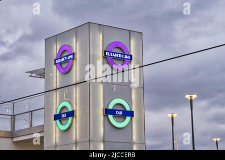 Panneaux ronds de métro londoniens illuminés pour Elizabeth Line en violet et DLR (train léger London Dockland) à Green, Londres Angleterre Royaume-Uni Banque D'Images