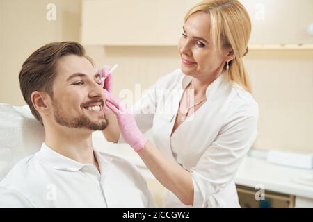 Femme de beauté application de contours sur le visage masculin Banque D'Images