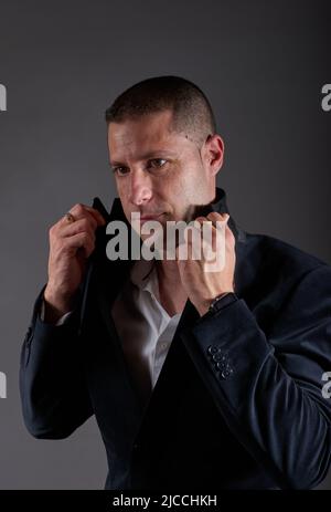 Un jeune homme dans une veste noire posant dans un studio. Banque D'Images