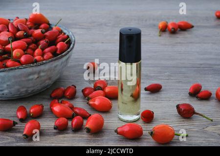 Rose chien (Rosa Canina) extrait d'huile de hanches rouges et fruits rouges naturels sur un bol Banque D'Images