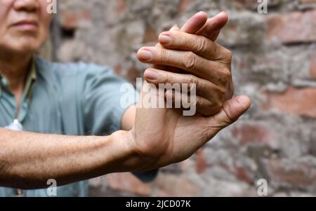 Renforcement de l'exercice pour les muscles du bras d'un homme asiatique aîné avec spasme musculaire. Banque D'Images