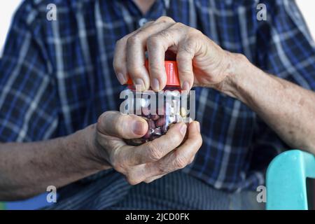 Homme chinois asiatique vissant le bouchon de la bouteille en verre. Concept de force et de puissance musculaire de la main. Banque D'Images