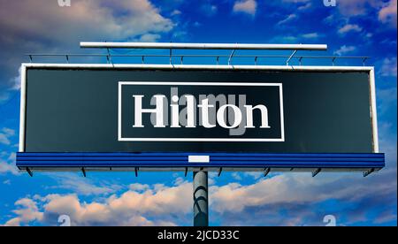 POZNAN, POL - 1 MAI 2022 : panneau publicitaire affichant le logo de Hilton Worldwide Holdings Inc., une société d'accueil qui gère et franchisage Banque D'Images