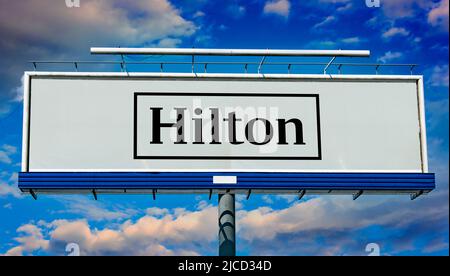 POZNAN, POL - 1 MAI 2022 : panneau publicitaire affichant le logo de Hilton Worldwide Holdings Inc., une société d'accueil qui gère et franchisage Banque D'Images