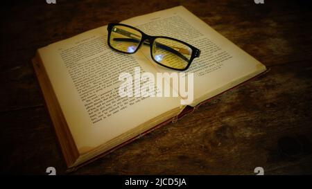 Un vieux livre et des verres se trouvent sur une table en bois Banque D'Images