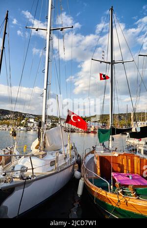 Vue sur la plage de Bodrum depuis la promenade. Bateaux à voile, yachts à la mer Égée avec des maisons blanches traditionnelles sur les collines de la ville portuaire de Bodrum en Turquie Banque D'Images