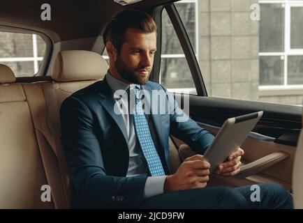Sérieusement homme d'affaires regardant l'écran de l'appareil moderne en auto Banque D'Images