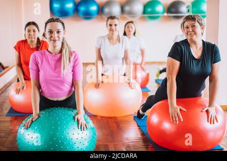 Groupe de femmes sont engagées dans la forme physique reposé leurs mains sur le fitball Banque D'Images