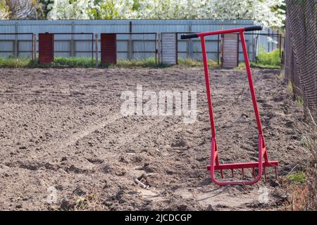 Pelle rouge sous forme de fourche dans le jardin. Pelle miracle, outil pratique. Cultivateur manuel. Le cultivateur est un outil efficace pour le travail du sol. Lit lo Banque D'Images