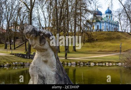 Sculpture en travertin - une figure d'un homme avec un lourd fardeau au bord de la marche menant à l'étang dans la colline du parc du château de Cesis, Lettonie Banque D'Images