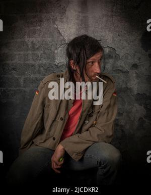 Junkie homme avec cheveux noirs et bouteille avec joint près de vieux mur de pierre Banque D'Images
