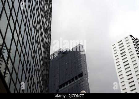 Façade d'un bâtiment moderne entouré de gratte-ciel qui réfléchit dessus Banque D'Images