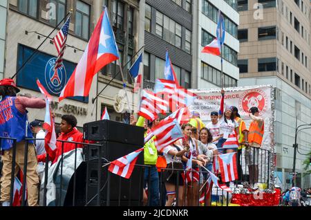 Les participants sont vus danser avec les drapeaux portoricains sur la Cinquième Avenue dans la ville de New York pendant la National Puerto Rican Day Parade, de retour après un Banque D'Images