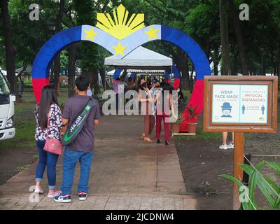 Manille, Philippines. 12th juin 2022. Les femmes sont vues à côté d'un arc de drapeau philippin le jour de l'indépendance. Les Philippins ont célébré le jour de l'indépendance en se rendant à la plage des Dolomites de Manille Baywalk pour savourer leurs vacances de fin de semaine. Ils s'attendaient à la réouverture de la plage, célèbre pour son sable blanc artificiel. Crédit : SOPA Images Limited/Alamy Live News Banque D'Images