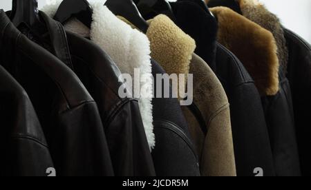 Collection de vestes en cuir sur cintres dans la boutique. De nombreuses nouvelles vestes d'hiver avec fourrure pour hommes. Arrière-plan et texture de gros plan en cuir, Banque D'Images
