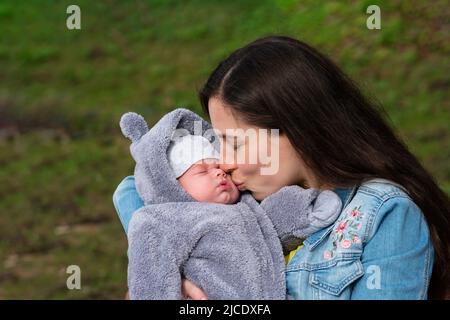 J'aime maman avec Newborn son sur ses bras à Spring Park. Сareful Mummy Kissing à l'adorable sommeil de l'enfant nouveau-né. La famille passe du temps ensemble sur la nature ou Banque D'Images