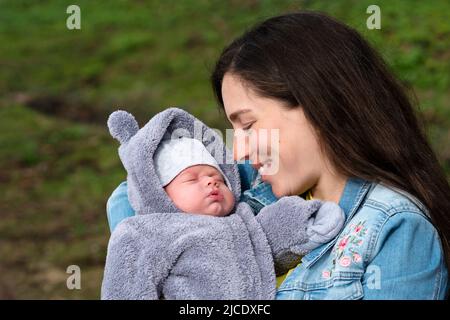 Aimer la mère avec le fils de nouveau-né sur ses bras à Spring Park. Сareful maman regarde mignon dormir nouvel enfant. La famille passe du temps ensemble sur nature O Banque D'Images