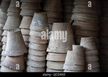 Gros plan des piles de pots de fleurs de terre cuite anciens et altérés dans le hangar de jardinage Banque D'Images