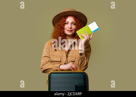 Une femme habillée dans un ensemble décontracté tient passeport, billet d'avion, carte d'embarquement et Suitcase. Voyageur de tourisme fille voyage en vacances. Pas de compagnie aérienne Banque D'Images