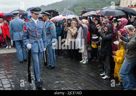 Les touristes regardent sous la pluie la cérémonie de la relève de la garde du château (Hradní stráž) devant le château de Prague sur la place Hradčanské à Prague, en République tchèque. Banque D'Images