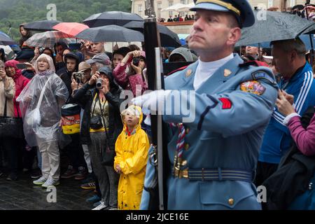 Les touristes regardent sous la pluie la cérémonie de la relève de la garde du château (Hradní stráž) devant le château de Prague sur la place Hradčanské à Prague, en République tchèque. Banque D'Images