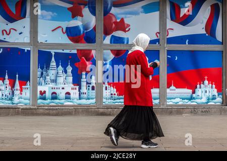 Moscou, Russie. 12th juin 2022 Une femme est vue devant une bannière dans les couleurs du tricolore russe lors d'une fête nationale connue sous le nom de jour de la Russie, célébrée le 12 juin, à la rue Tverskaya à Moscou, en Russie. Nikolay Vinokurov/Alay Live News Banque D'Images