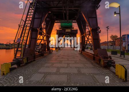 Des grues historiques sur les boulevards au bord de la rivière à Szczecin pendant un lever de soleil spectaculaire Banque D'Images