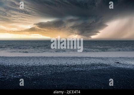 Vue panoramique sur la plage noire de Reynisfjara contre un ciel nuageux au coucher du soleil Banque D'Images