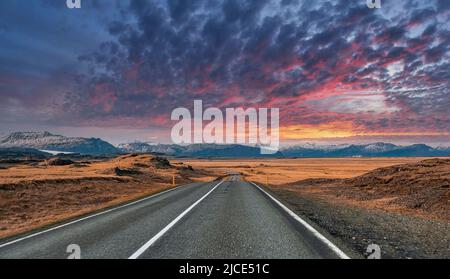 Route de fuite vide au milieu du paysage volcanique contre ciel nuageux pendant le coucher du soleil Banque D'Images