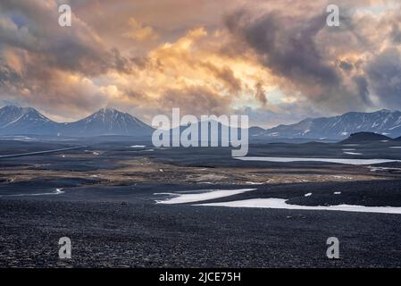Vue panoramique sur la neige sur le paysage volcanique contre les montagnes au coucher du soleil Banque D'Images