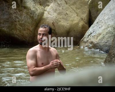 Cisneros, Antioquia, Colombie - 20 février 2022: Homme blanc baignade dans la rivière entourée de rochers Banque D'Images