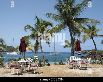 Vue sur les tables et les chaises vides sur une jolie plage de sable d'Antigua Banque D'Images