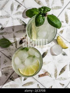Deux cocktails margarita avec citron vert et basilic sur carreaux imprimés. Orientation verticale. Vue de dessus Banque D'Images