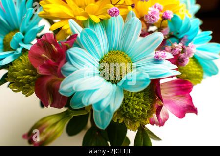 Bouquet délicat de chrysanthèmes jaunes et bleus sur une table blanche près de la fenêtre, gros plan. Banque D'Images