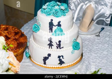 Beau gâteau de mariage. Gâteau blanc à trois niveaux avec roses bleues et figurines des jeunes mariés Banque D'Images