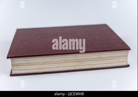 Le grand livre rouge sur fond neutre. Livre fermé avec pages jaunrées. Encyclopédie de couverture rigide. Gros plan. Mise au point sélective. Banque D'Images