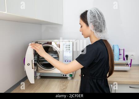 Infirmière stérilisant les instruments médicaux en autoclave dans la clinique madicale Banque D'Images