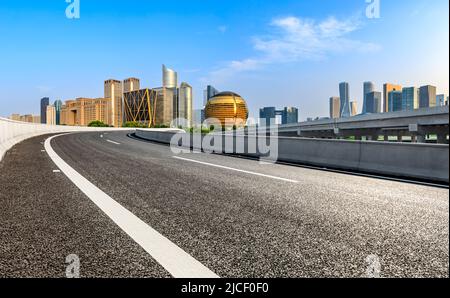 Route asphaltée et horizon de la ville avec des bâtiments commerciaux modernes à Hangzhou, en Chine. Banque D'Images