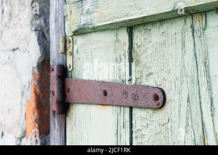 Arrière-plan de la porte en bois antique. Fragment de l'ancienne porte avec des restes de peinture verte et des charnières rouillées Banque D'Images