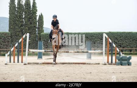 Un enfant sur un cheval sautant sur la barrière. Banque D'Images