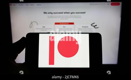 Personne détenant un smartphone avec le logo de la société américaine de plate-forme d'adhésion Patreon Inc. À l'écran devant le site Web. Mise au point sur l'affichage du téléphone. Banque D'Images