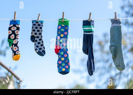 Chaussettes seules différentes sans partenaire sur une corde à linge, image symbole 'Lost Socks Memorial Day'. Banque D'Images