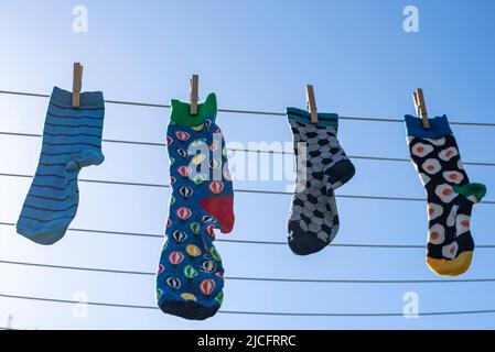 Chaussettes seules différentes sans partenaire sur une corde à linge, image symbole 'Lost Socks Memorial Day'. Banque D'Images