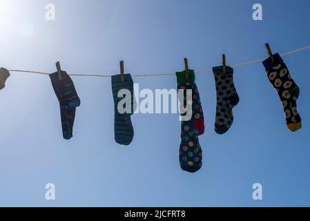 Chaussettes seules différentes sans partenaire sur une corde à linge, image symbole 'Lost Socks Memorial Day'. Banque D'Images