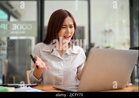Insatisfait femme d'affaires asiatique ou patron de femme insatisfait et se fâche après avoir lu un e-mail d'affaires de son fournisseur sur ordinateur portable. Banque D'Images