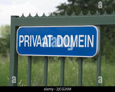 Plaque bleue avec des lettres blanches sur une clôture qui dit domaine privé en néerlandais Banque D'Images